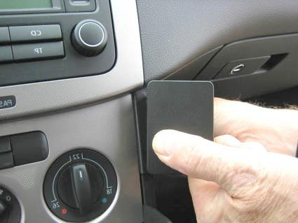En hand pekar på en svart panel i en bilinteriör.