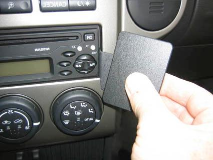 En hand som håller en svart kortplatta nära bilens kontrollpanel.