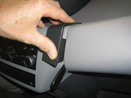 Hand som fäster en vinklad monteringsbygel på en bilinteriör.