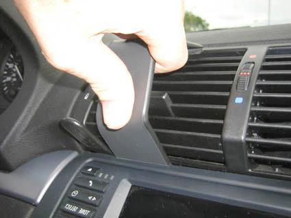 En hand tar bort en del av ventilationssystemet i en BMW X5.