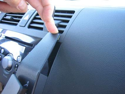 Hand som justerar en del av instrumentbrädan i en Suzuki Swift 05-10.