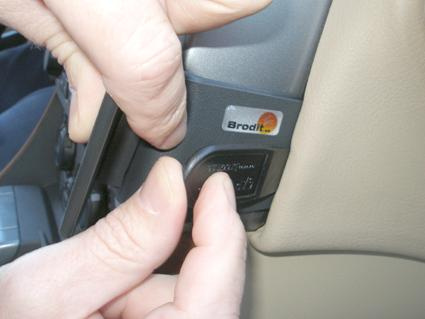 En hand trycker på en knapp i en bilinteriör.