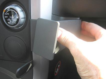 En hand som drar ut en vinklad hållare i en bilinteriör.