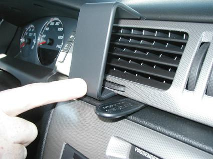 En hand pekar på en ventilationsöppning i en bilinteriör.