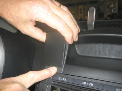 En hand som placerar ett svart föremål på instrumentbrädan i en bil.