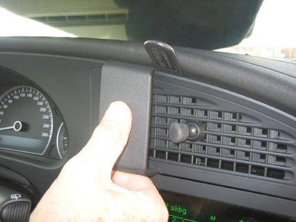 Handen trycker på en del av bilens interiör, nära instrumentbrädan och luftventilen.