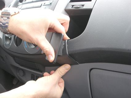 En hand tar bort en panel i ett bilinteriör.