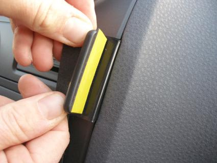 En hand sätter fast en gul remsa på en bilnyckel eller liknande detalj.