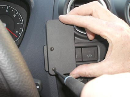 En hand skruvar fast en panel på instrumentbrädan i en Ford Fiesta.