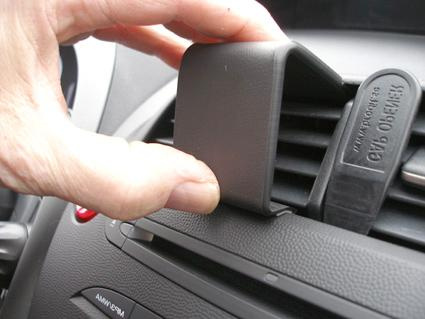 En hand fäster en ventilationsgrill på en bilpanel.