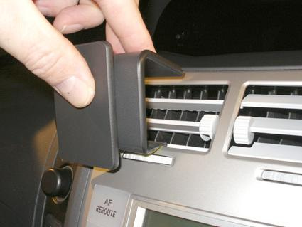 En hand fäster en beklädnad på luftutloppet i en Toyota Yaris.