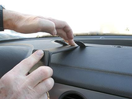 En hand justerar en del av instrumentbrädan i en bil.