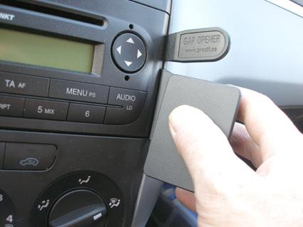 En hand håller en grå plastdel vid instrumentpanelen i en Fiat Punto.