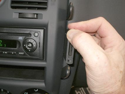 En hand justerar en del av bilens interiör, nära stereon.