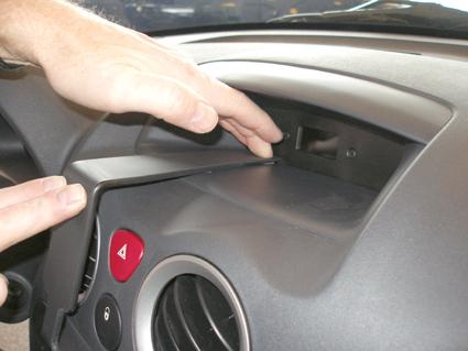 En hand justerar en komponent i instrumentpanelen på en Citroen C2/C3.