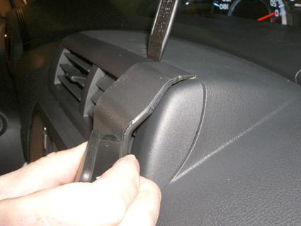 En hand håller i en del som monteras på instrumentpanelen.