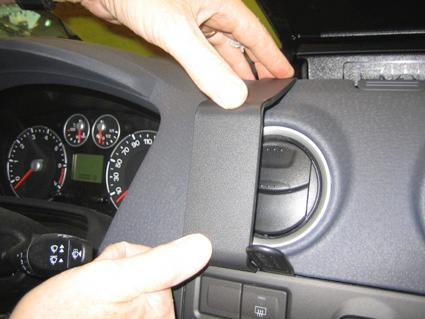 En person justerar en panel ovanför en luftventil i en bil.