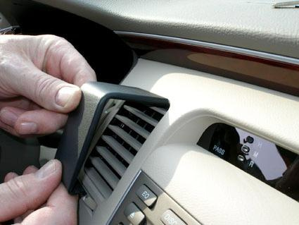 En hand tar bort en ventilpanelexemplare från en bils instrumentbräda.