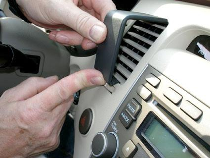 En hand monterar ett föremål på bilens panel.