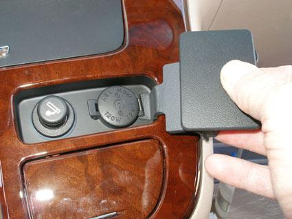 En hand öppnar en del av instrumentpanelen med kontroller och låda.