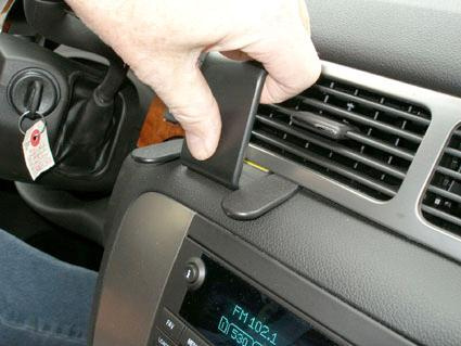 En hand placerar en del på instrumentpanelen i en Chevrolet Avalanche.