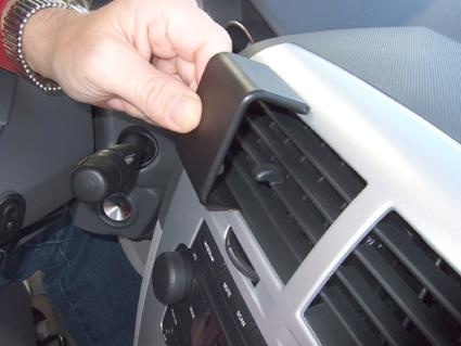 En hand som fäster en svart del på en bils ventilationsgaller.