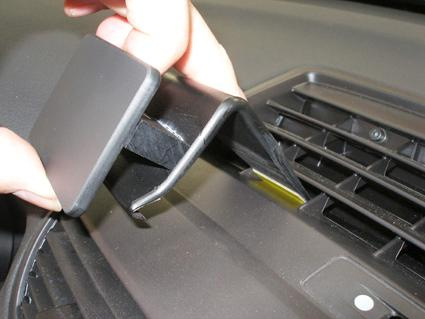 En hand håller i en svart plastdel som verkar kopplas till bilens ventilationssystem.