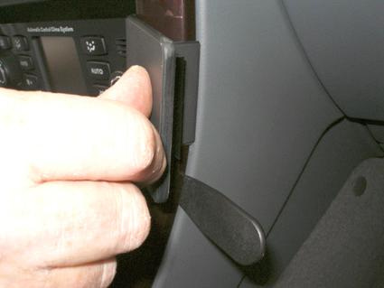 En hand greppar en svart spak i en bils inredning.