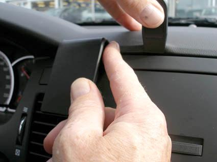 En hand installerar en del på en bilinteriör.