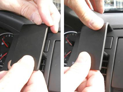 En hand som håller en svart plastdel, troligtvis en bilkomponent.