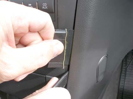 En hand håller i en komponent vid bilens instrumentpanel.