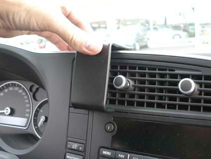 En hand håller i en plastdel som sitter vid mittpanelen i en Saab 9-3.