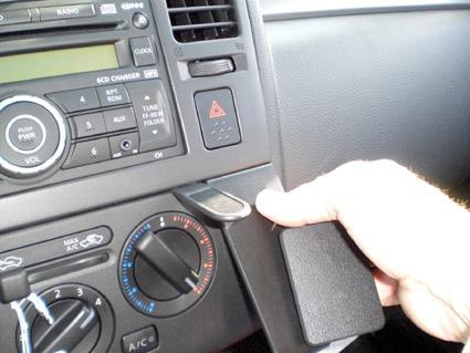 Bilden visar en bilinteriör med en hand som håller i en panel vid kontrollpanelen.