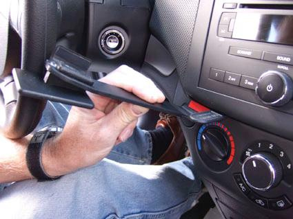 En hand håller i en del av instrumentbrädan i en Chevrolet Aveo.