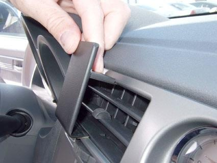 En hand placerar en monteringsbygel i bilens instrumentbräda.