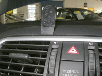 En del av en bilinteriör med luftventiler och säkerhetsknapp.