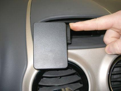 En hand trycker på en svart plastlucka på instrumentpanelen.