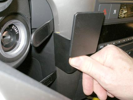 En hand justerar en svart knapp på en bilinteriör.