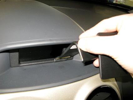 En hand öppnar en ficka på instrumentbrädan i en Opel Corsa.