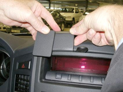 Två händer monterar en del på bilens instrumentpanel.