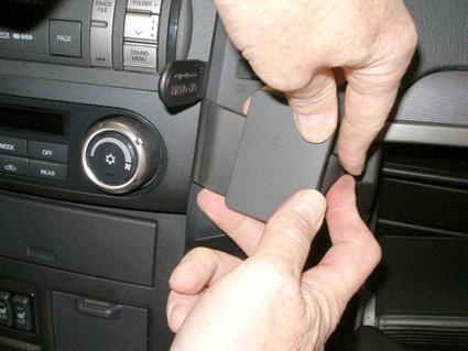 Bilden visar en person som installerar en enhet i Mitsubishi Pajeros interiör.