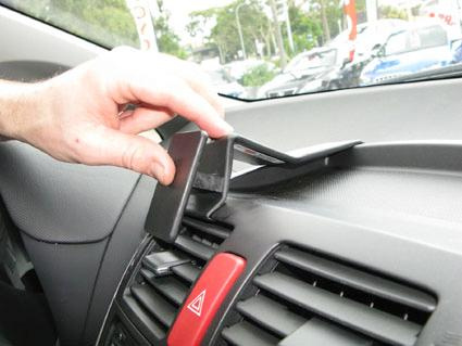 En hand som fäster en hållare på bilens instrumentbräda.