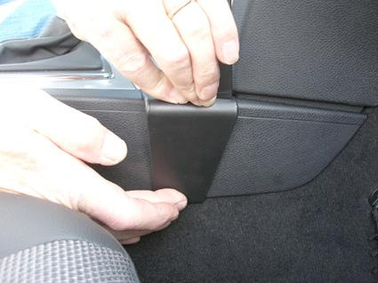 En person som installerar eller justerar en del av interiören i en Mercedes Benz C-Klass.