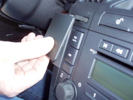 En hand installerar en enhet i bilens instrumentpanel.