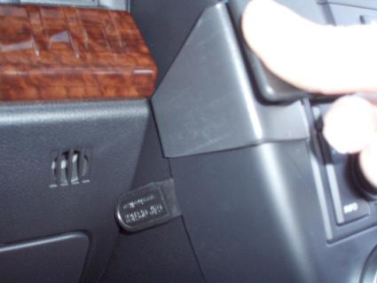 En hand trycker på en spak i en bilinteriör, nära en nyckel.