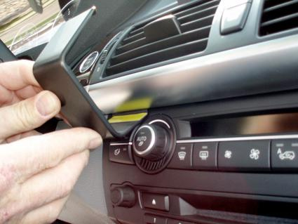 En hand placerar en komponent på instrumentbrädan i en BMW.