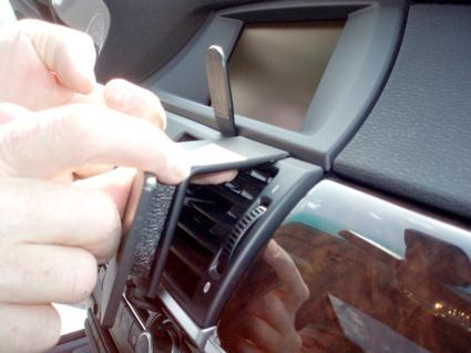 En hand justerar aircondition-ventilen i en BMW X5/X6-interiör.