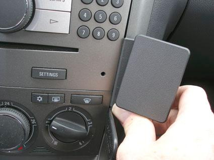 En hand som håller en enhet nära bilens kontrollpanel och knappar.