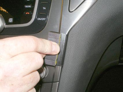 En hand som trycker på en knapp i en bils instrumentpanel.