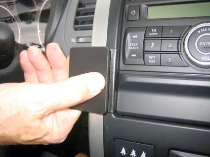 En hand placerar en svart säkerhetsklämma på bilens interiör.